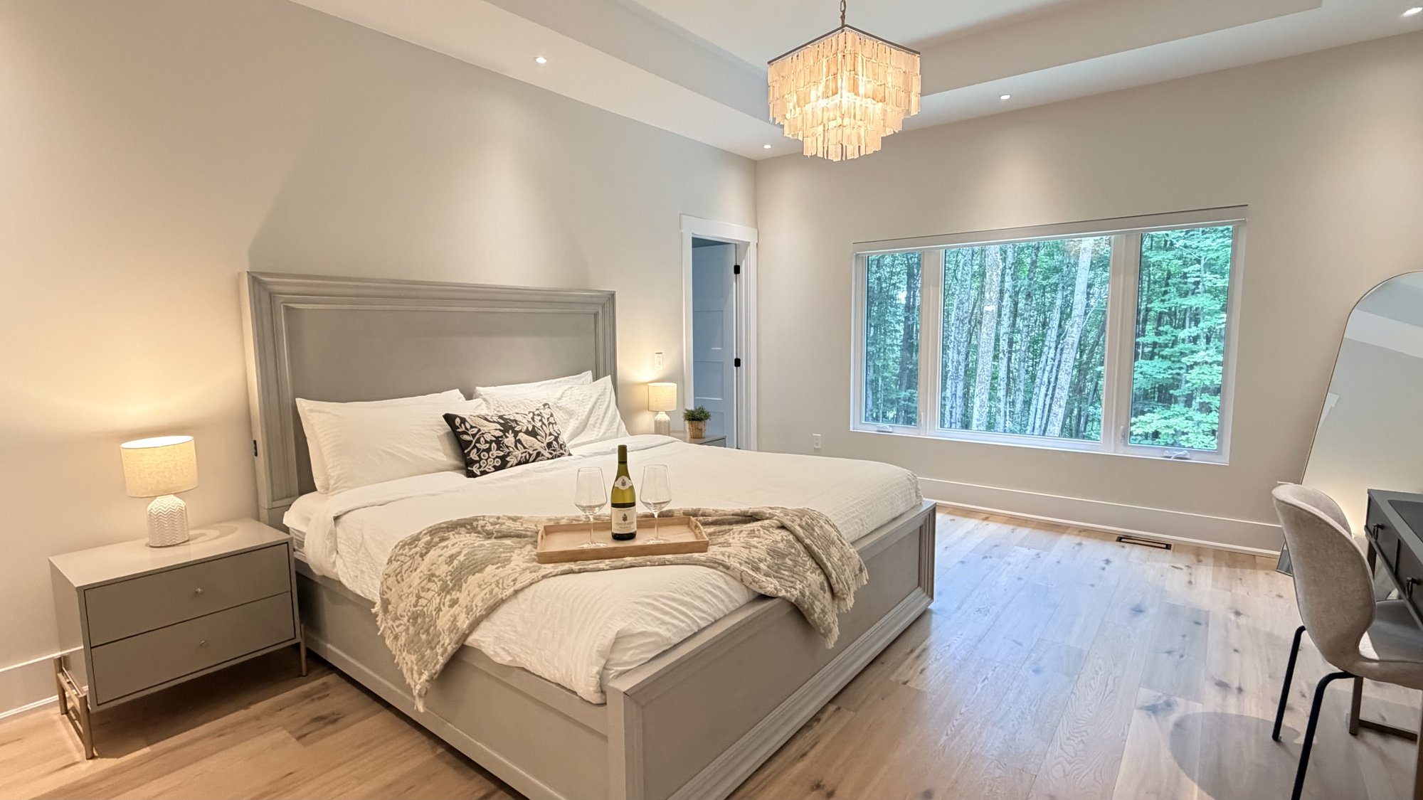 Master bedroom with chandelier and forest windows