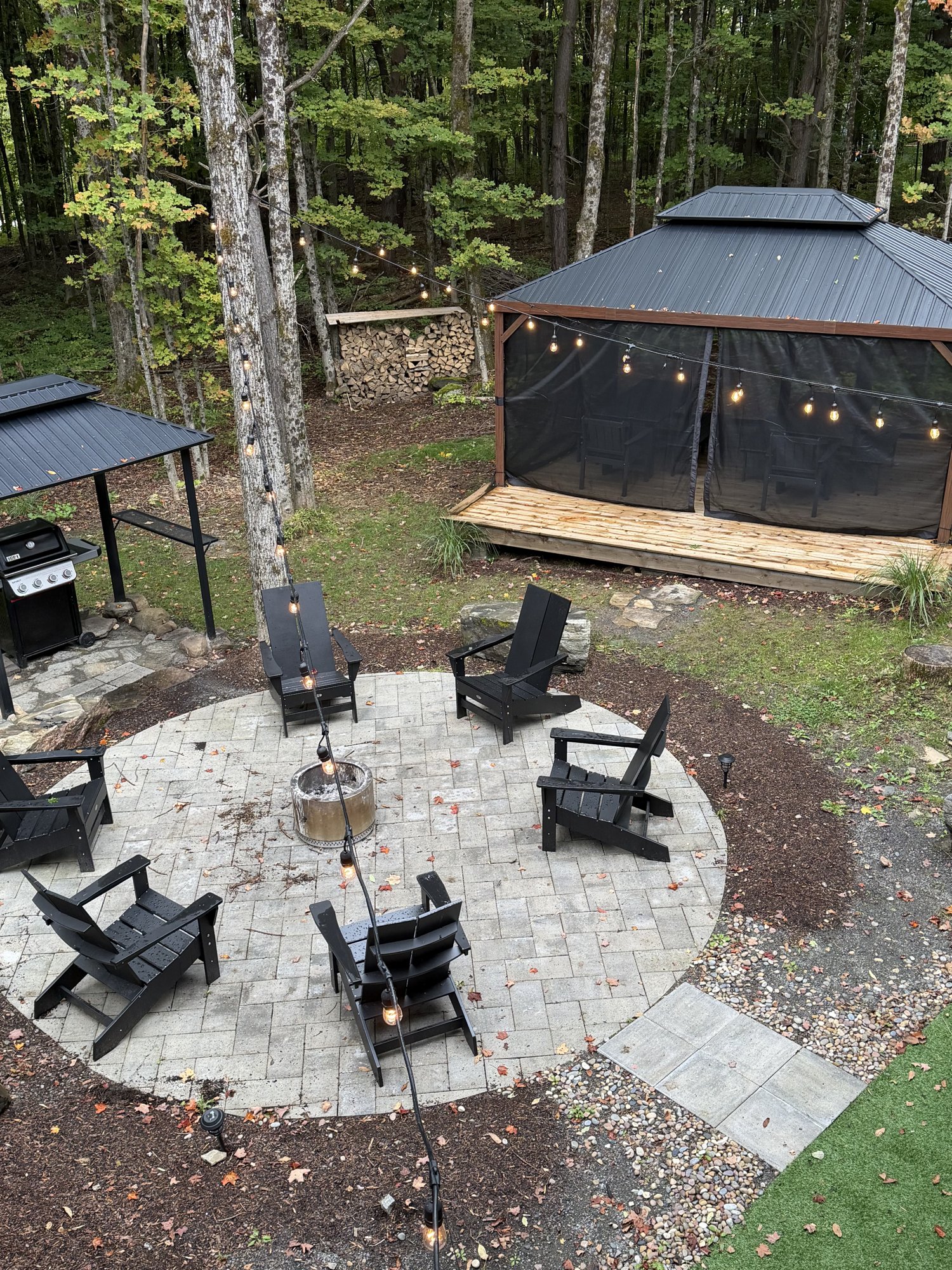 Evening aerial — firepit and gazebo lit with string lights